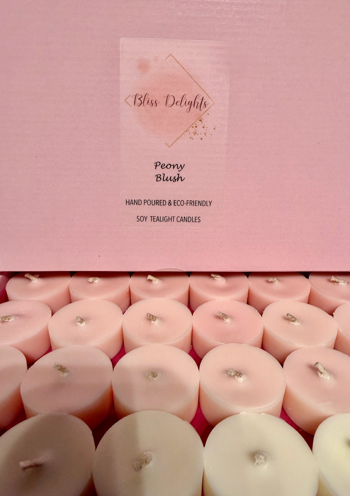 Bliss Delights Peony Blush soy wax tealights in blush pink and ivory, arranged in an open pink box with branded packaging. Hand-poured candles with cotton wicks.