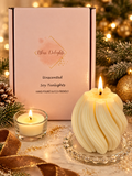 Bliss Delights pink box of unscented soy tealights displayed with a lit ivory Twirl soy pillar candle and glass tealight holder, styled with festive greenery, gold ribbon and warm Christmas lights.