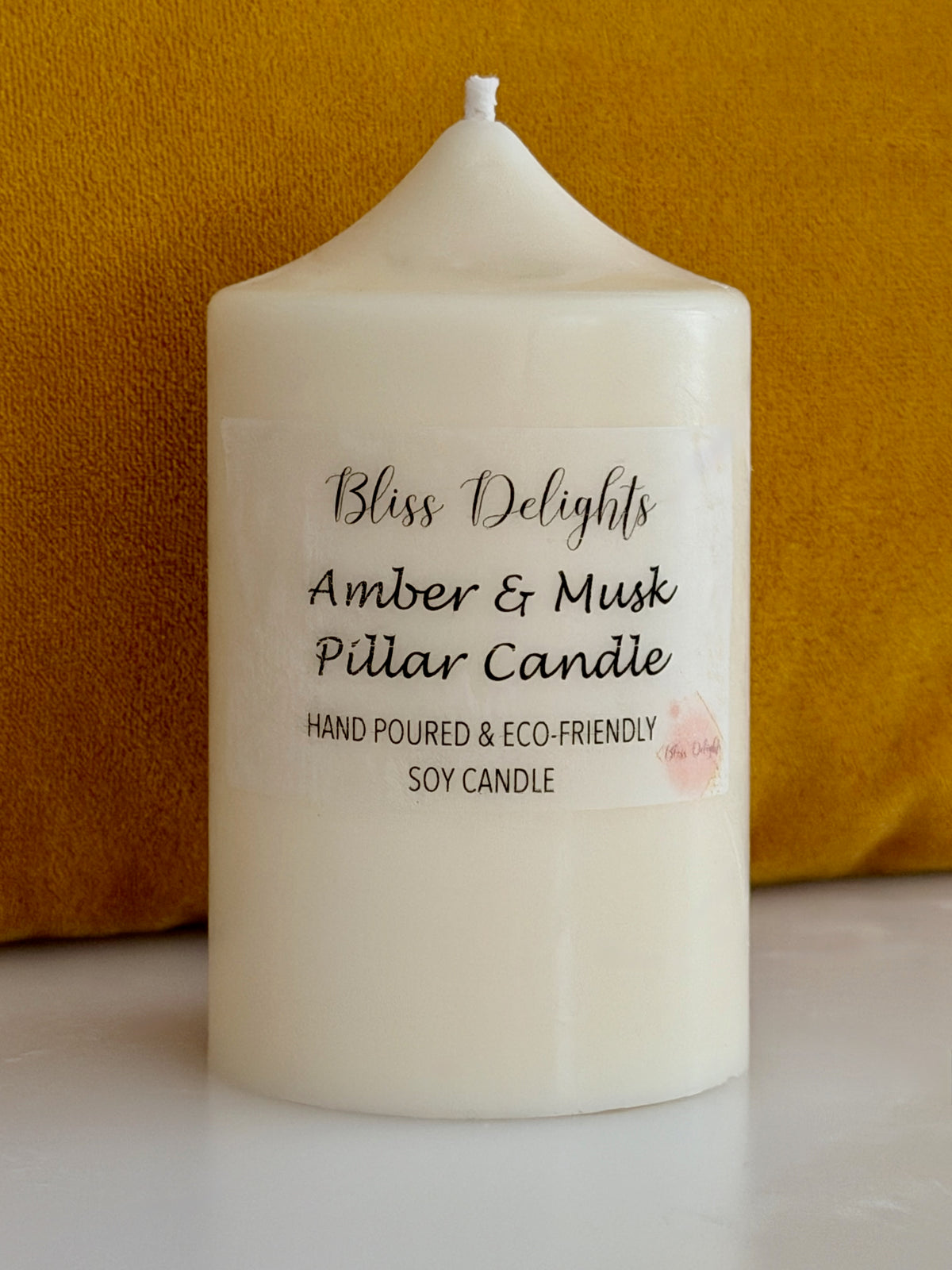 Ivory soy wax pillar candle by Bliss Delights, featuring an Amber & Musk label with a hand-poured and eco-friendly design.