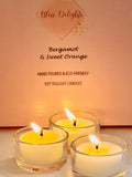 Three glowing Bergamot and Sweet Orange soy wax tealights in reusable clear glass holders, displayed against Bliss Delights pink packaging. Handmade candles with a warm golden glow and a fresh citrus fragrance.