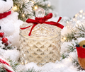 Bliss Delights pearlescent diamond soy candle in a faceted glass jar with a red ribbon, styled with snowy foliage, warm fairy lights and festive Christmas decorations.