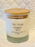 Bliss Delights Pumpkin Spice soy candle in a clear glass jar with a natural bamboo lid, displayed against a cream quilted background.