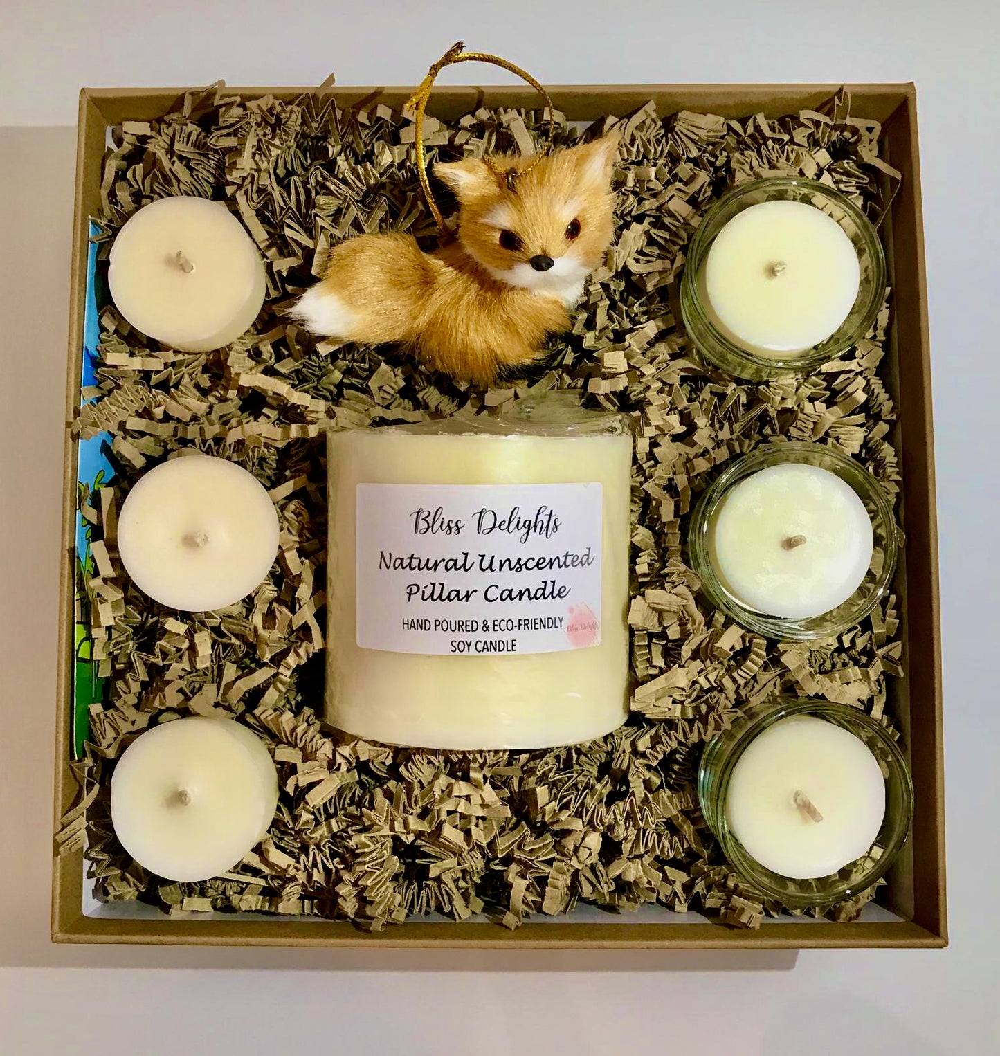 Box of candles with a fox figurine on a white background
